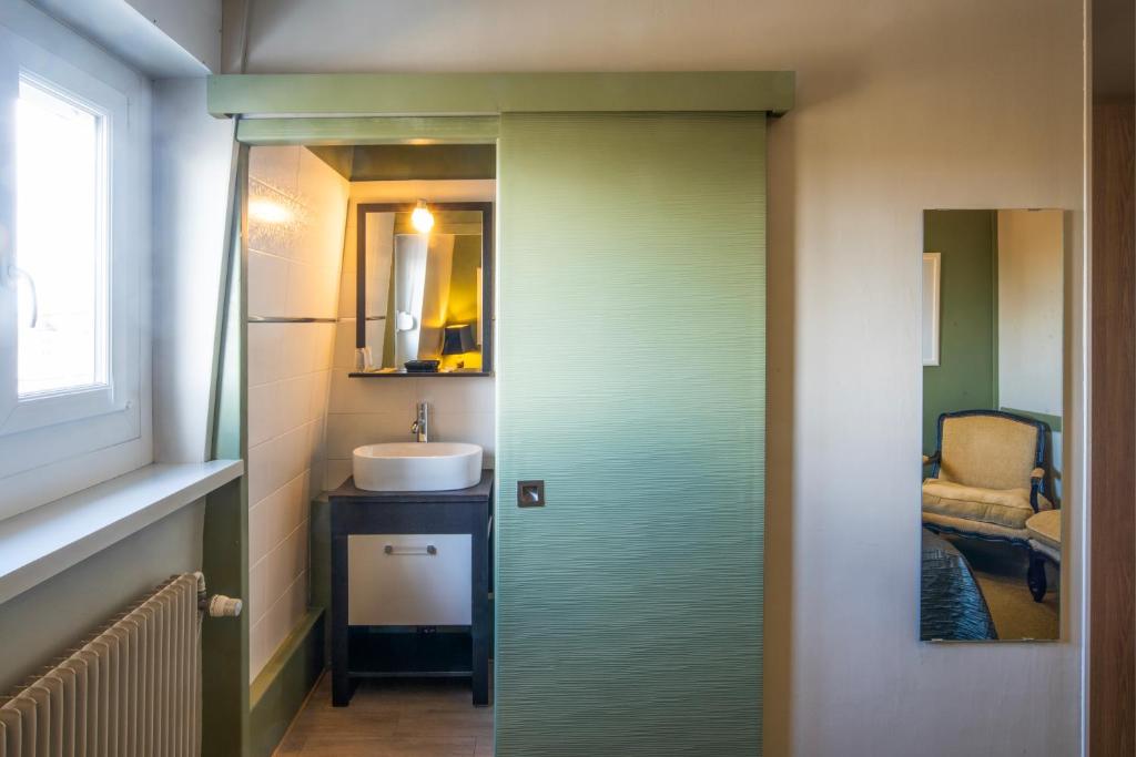 a bathroom with a door leading to a sink at Hotel La Chope in Cambrai