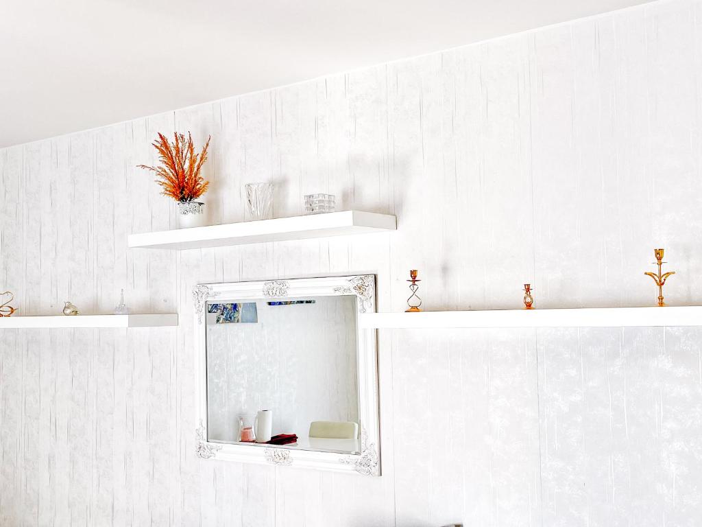 a bathroom with white walls and a mirror and shelves at Ilona Apartments -"Home Away From Home" in Kotka
