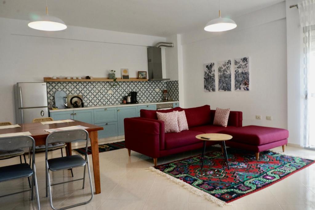 ein Wohnzimmer mit einem roten Sofa und einem Tisch in der Unterkunft Lovely 2 bedroom condo with free parking in Vlorë