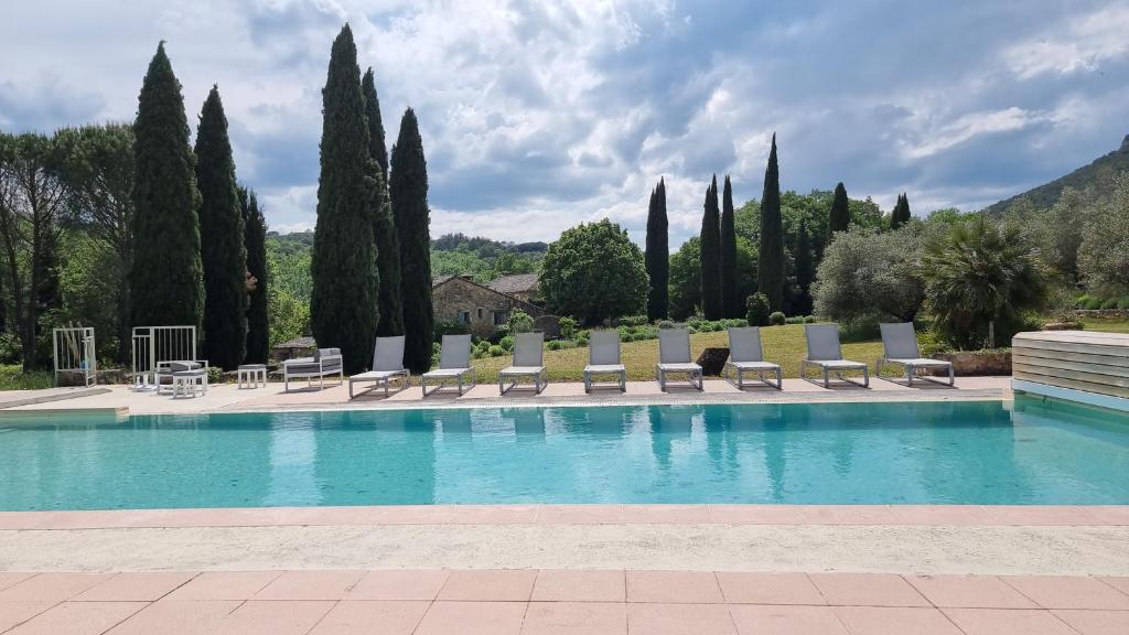 a swimming pool with lounge chairs and trees at Domaine du Moulin de Cors in La Roque-sur-Cèze