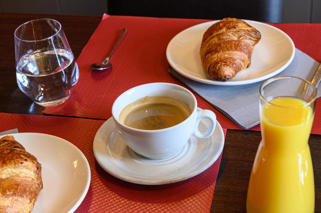 a table with plates of food and a cup of coffee and croissants at Hotel La Chope in Cambrai