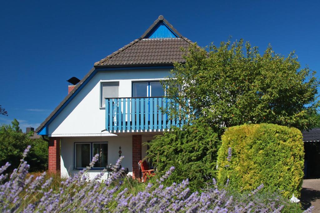 ein weißes Haus mit einem Balkon und lila Blumen in der Unterkunft Ferienhaus Uli in Wustrow