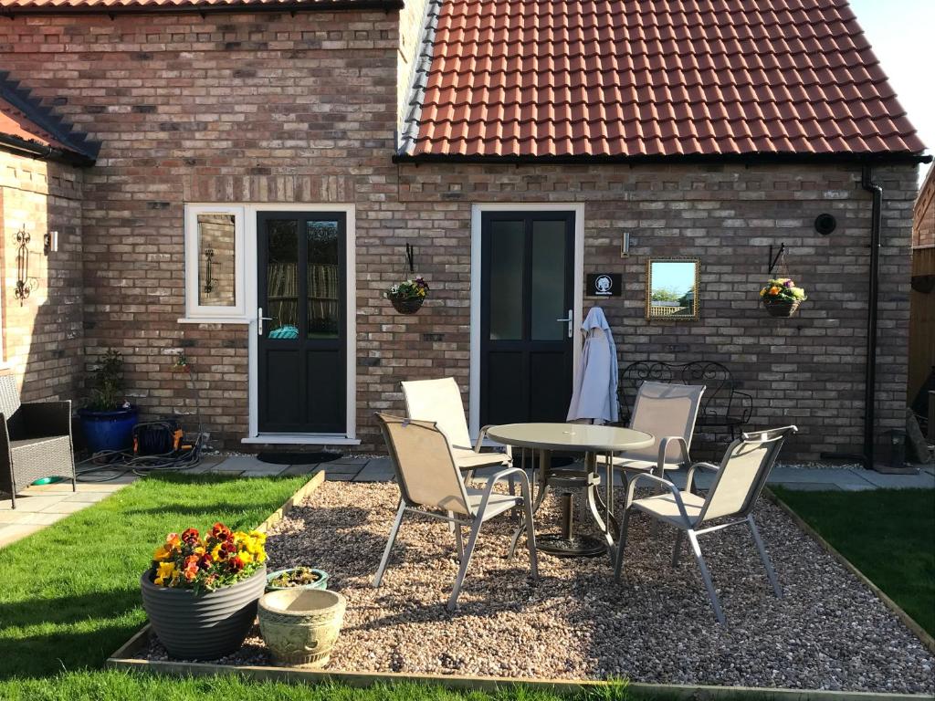 a patio with a table and chairs in front of a house at HomeForYou - Holiday Home in the Wolds in Spilsby