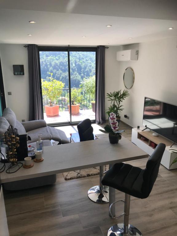 a living room with a table and a large window at Appartement 2 pièces - Le Berceau in Castellar