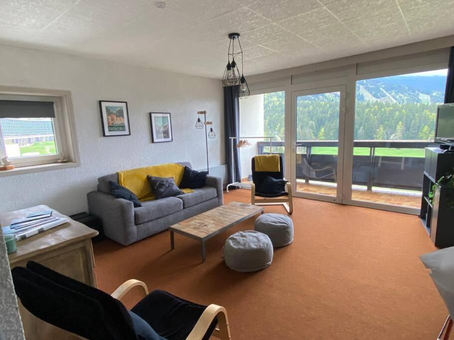 sala de estar con sofá, mesa y sillas en Appartement 50m2 vue imprenable avec garage draps et serviettes compris en Villard-de-Lans
