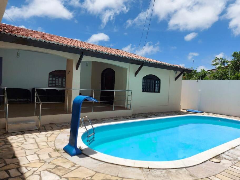 a swimming pool in front of a house at Casa agradável com piscina, ar condicionado e churrasqueira in Natal