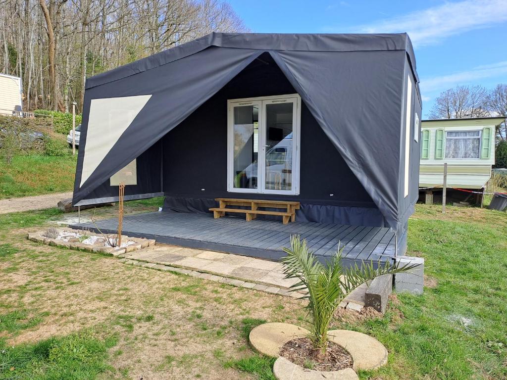 Camping le Bois Jahan في Brunelles: خيمة سوداء مع مقعد في ساحة