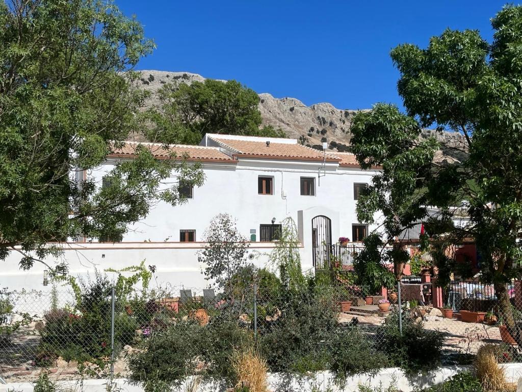 uma casa branca com uma montanha ao fundo em El Retiro em Loja