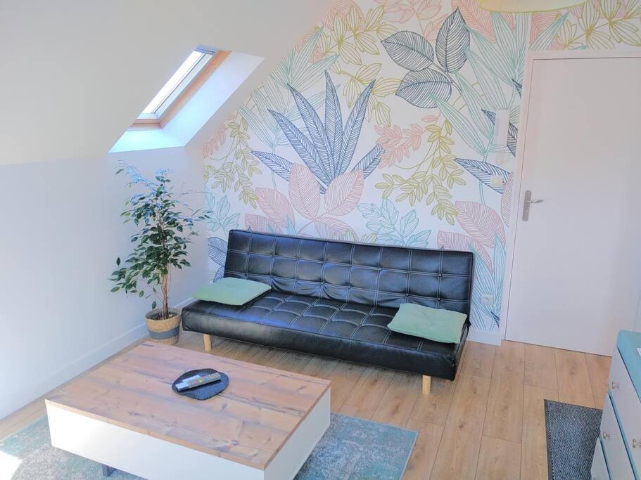 uma sala de estar com um sofá de couro preto e uma mesa em SOUS LES TOITS em Troyes