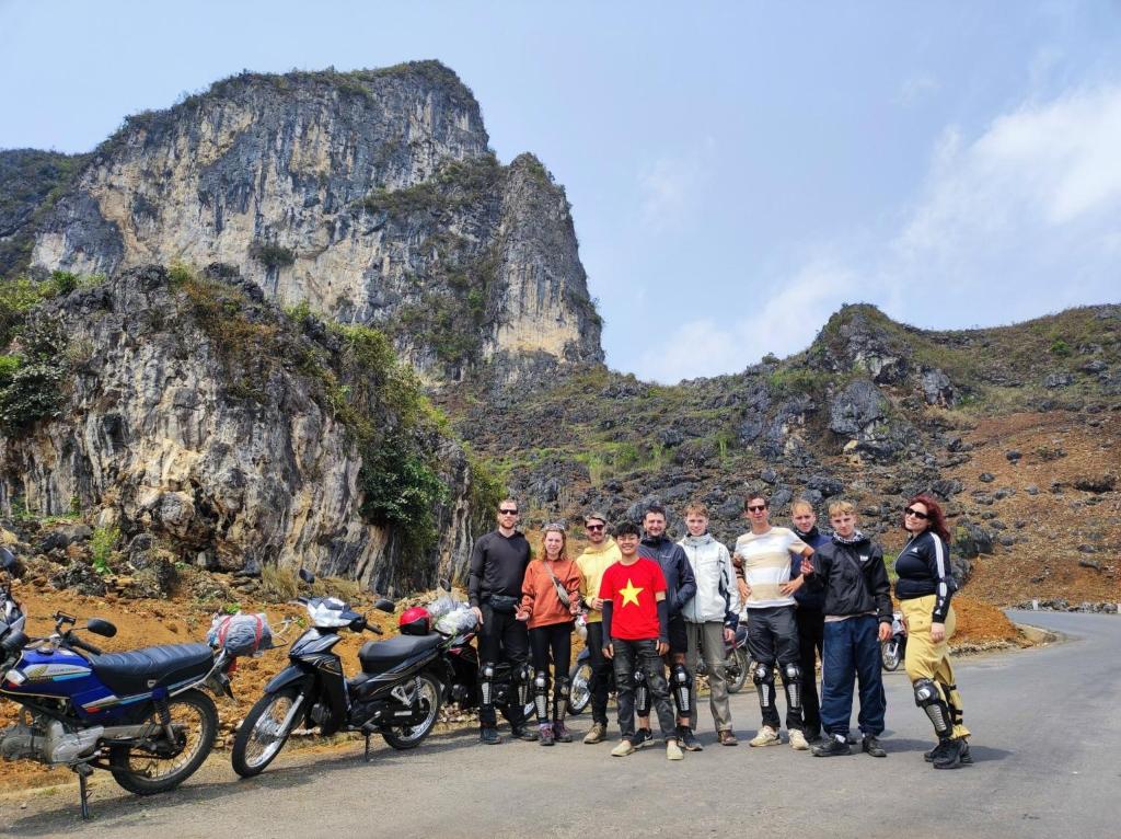 a group of people standing next to motorcycles on a road at Bong Hostel and Motorbike Tour in Ha Giang