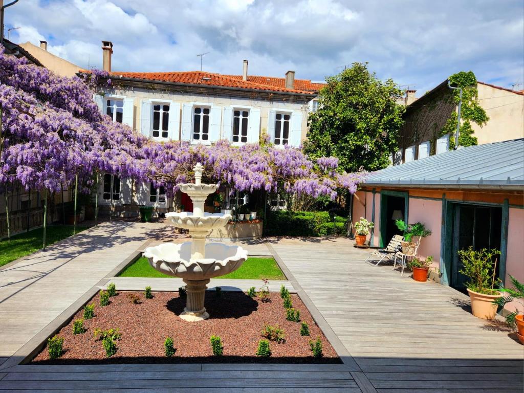 una fuente en el patio de una casa con flores púrpuras en Maison centre historique Le Préau saint Jacques, en Castres