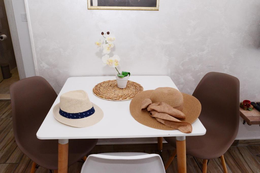 ein weißer Tisch mit zwei Hüten und einer Blumenvase in der Unterkunft LightHouse Apartments in Tivat