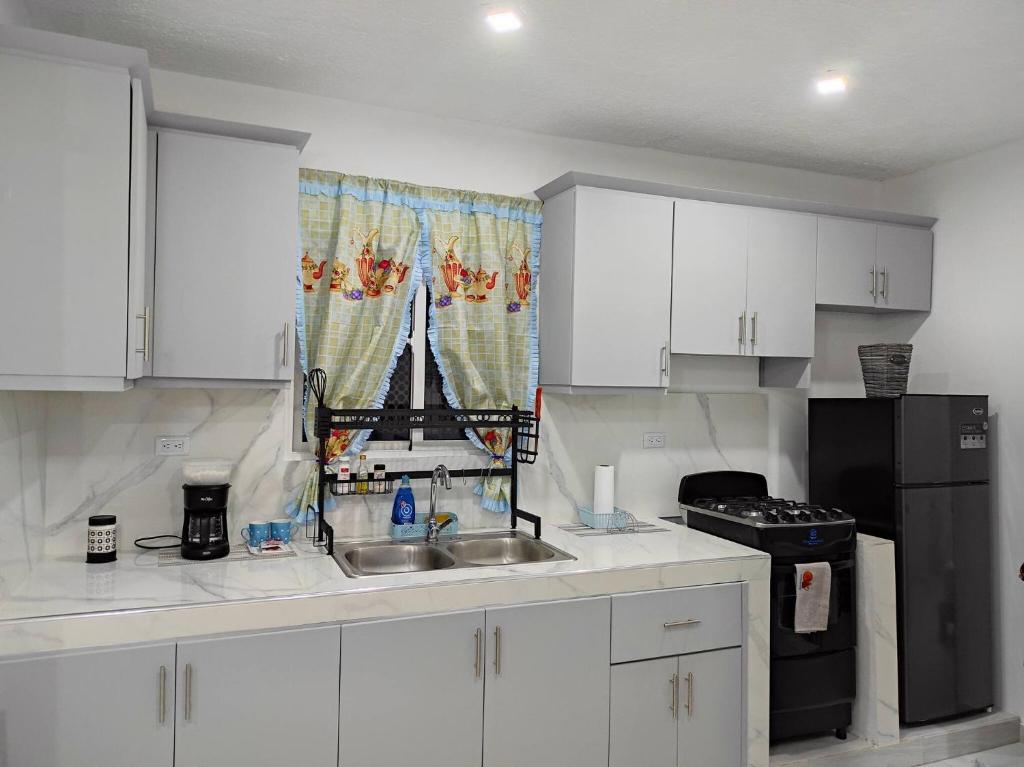 a kitchen with white cabinets and a sink and a window at 100 Mts From Malecon Weeklymonthly Discount in Santa Bárbara de Samaná