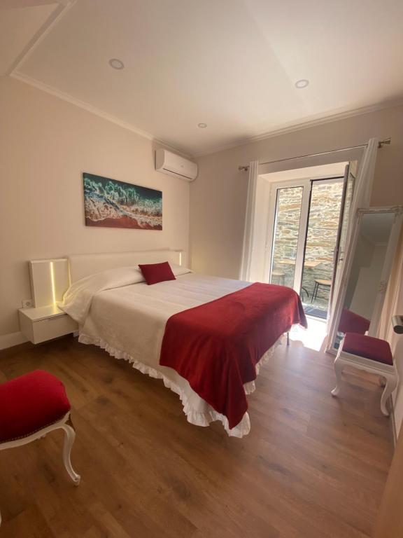 - une chambre avec un grand lit et une couverture rouge dans l'établissement Apartamentos Barbosa, à Vila Nova de Foz Coa