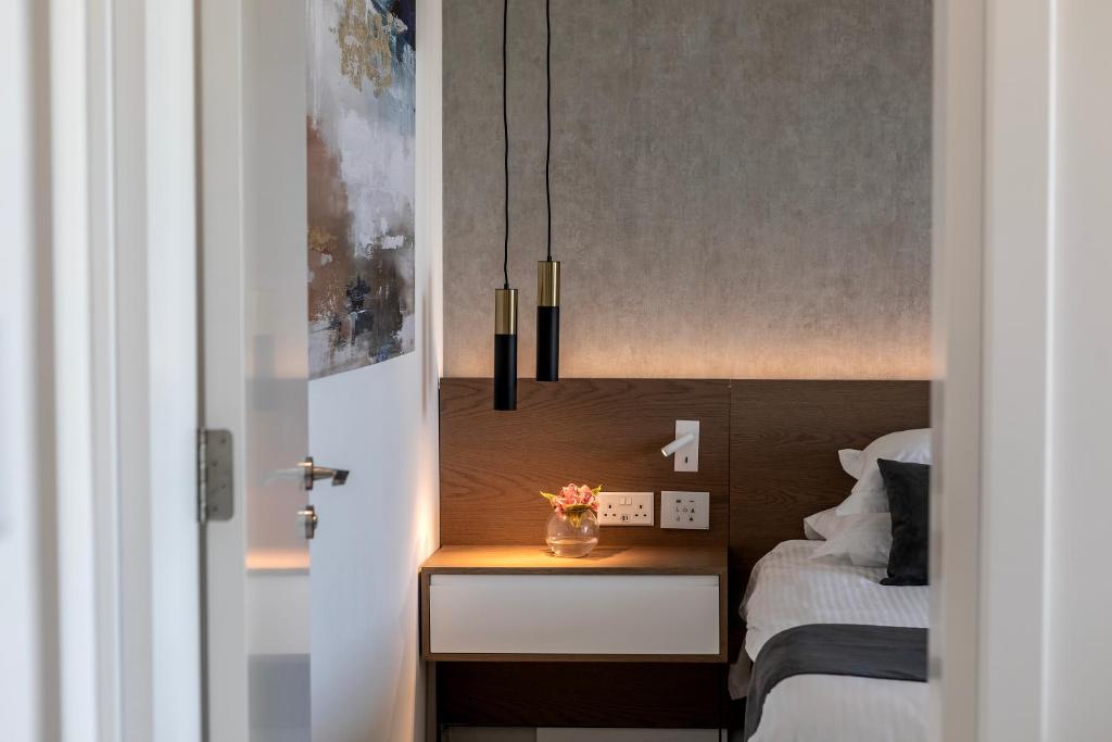 a bedroom with a bed and a nightstand with a table at Pavlo Napa Beach Hotel in Ayia Napa
