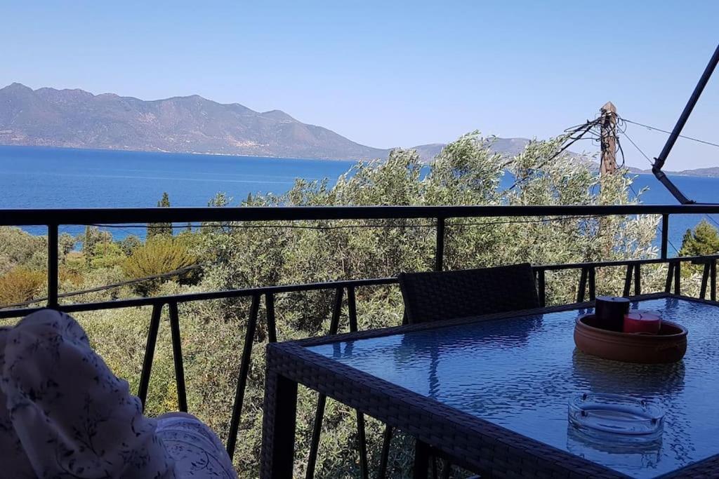 una mesa en un balcón con vistas al agua en 'Magic Of Nature' Cottage With a Breathtaking View, en Dhriópi