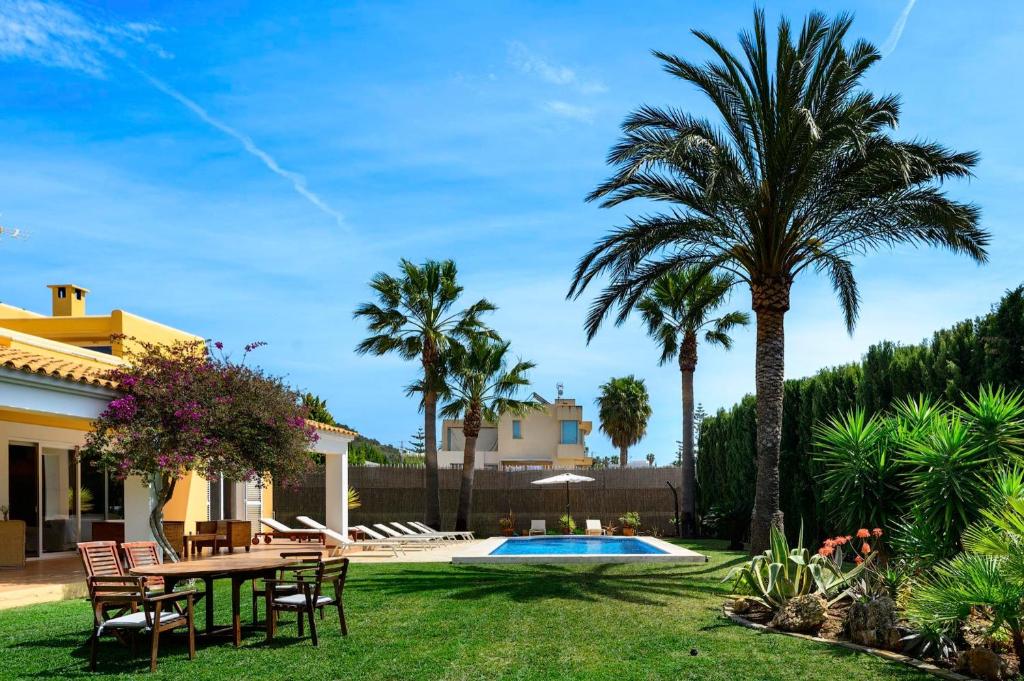 een achtertuin met een tafel en stoelen en een zwembad bij Villa Cali in San Jose de sa Talaia