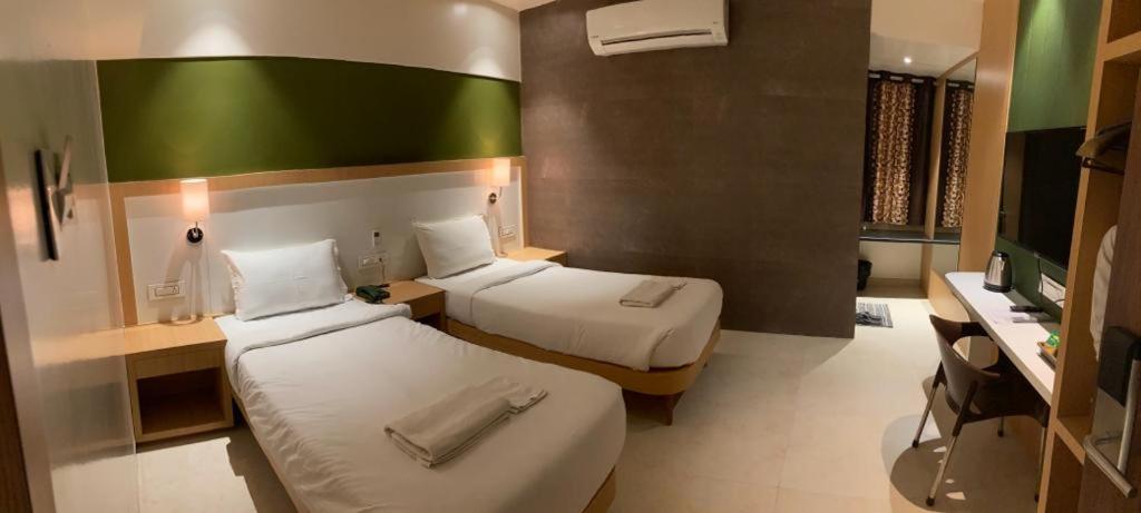 a hotel room with two beds and a desk at Hotel Palash Inn in Yavatmāl