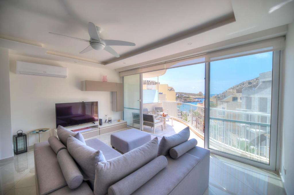 a living room with a couch and a large window at Seaside apartment in the heart of Xlendi Gozo in Xlendi