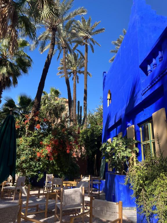 een blauw gebouw met stoelen en palmbomen bij Résidence Mirador MAJORELLE in Marrakesh