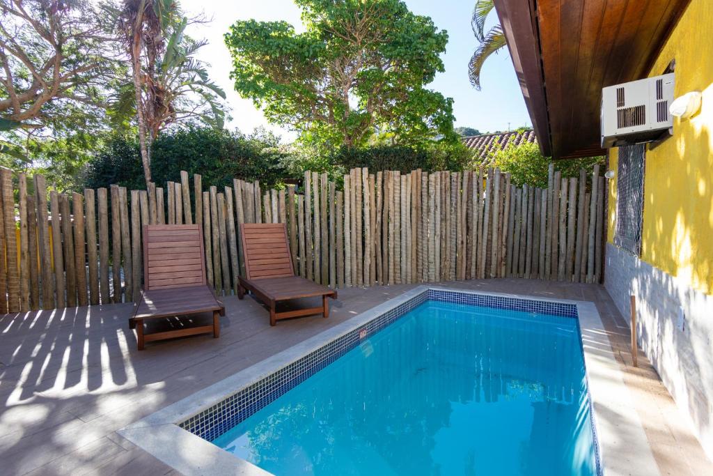 uma piscina com duas cadeiras ao lado de uma cerca de madeira em Praia da Ferradura com quatro suítes e piscina. em Búzios