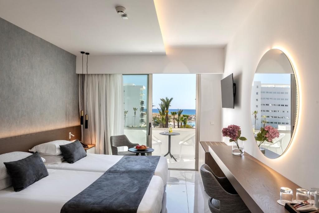 a hotel room with a bed and a large window at Pavlo Napa Beach Hotel in Ayia Napa