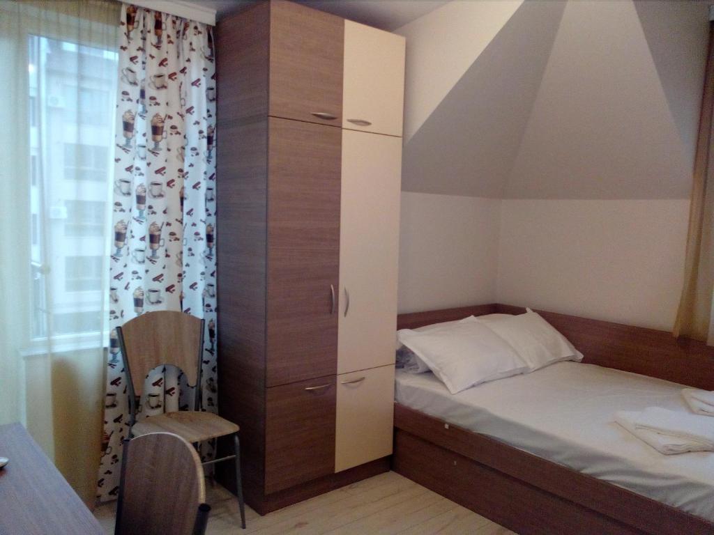 a small bedroom with a bed and a tall cabinet at Хостел Атлас - Hostel Atlas in Blagoevgrad