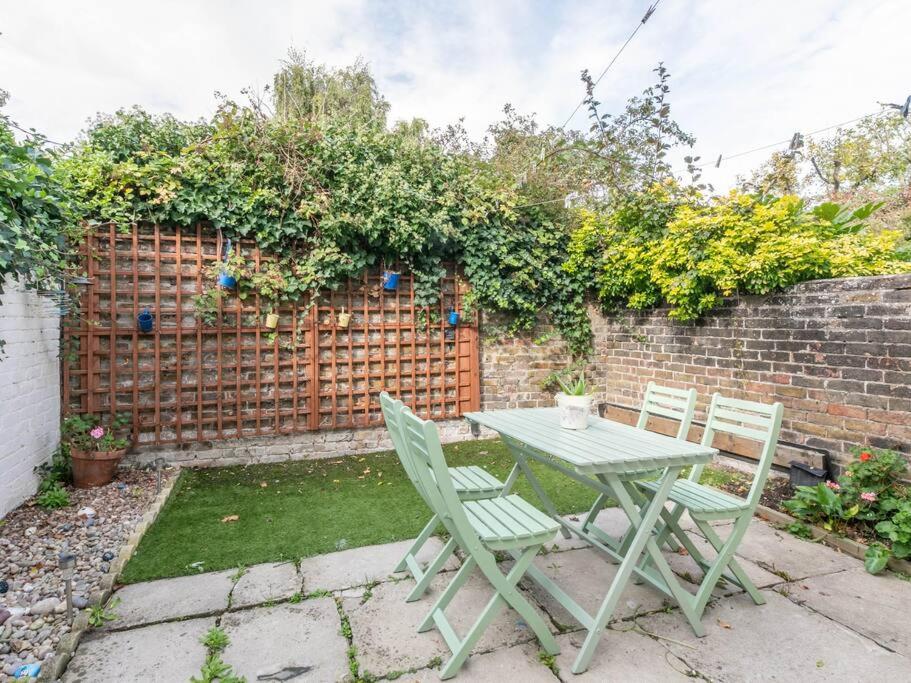 a table and chairs in a garden with a fence at Cute and Cosy 2 Bed on a Peaceful street in Kent