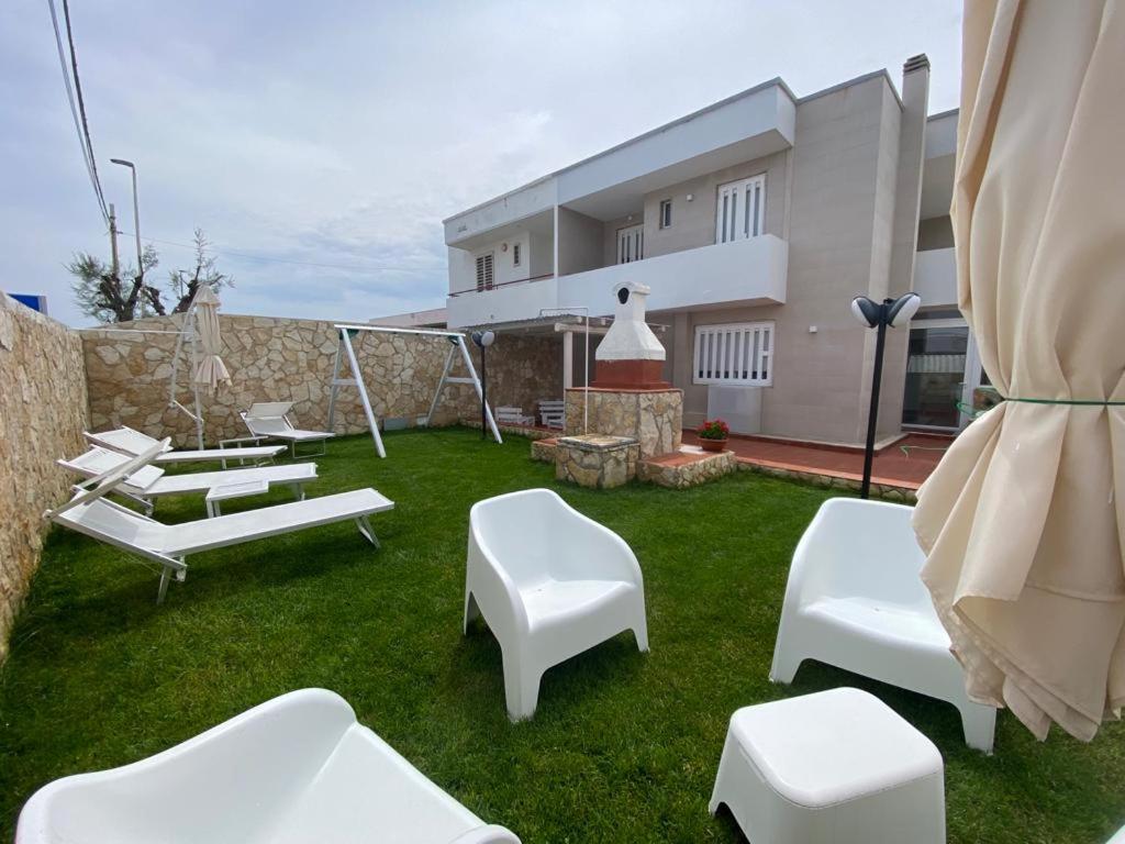 um quintal com cadeiras brancas e um edifício em La maison du mar em Bari