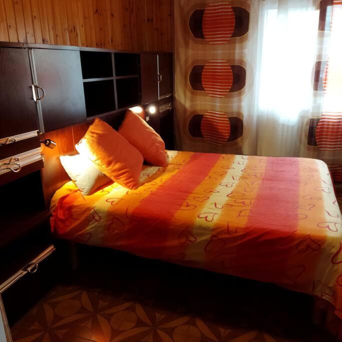 sypialnia z łóżkiem z pomarańczową pościelą i oknem w obiekcie La Cueva w mieście Imola