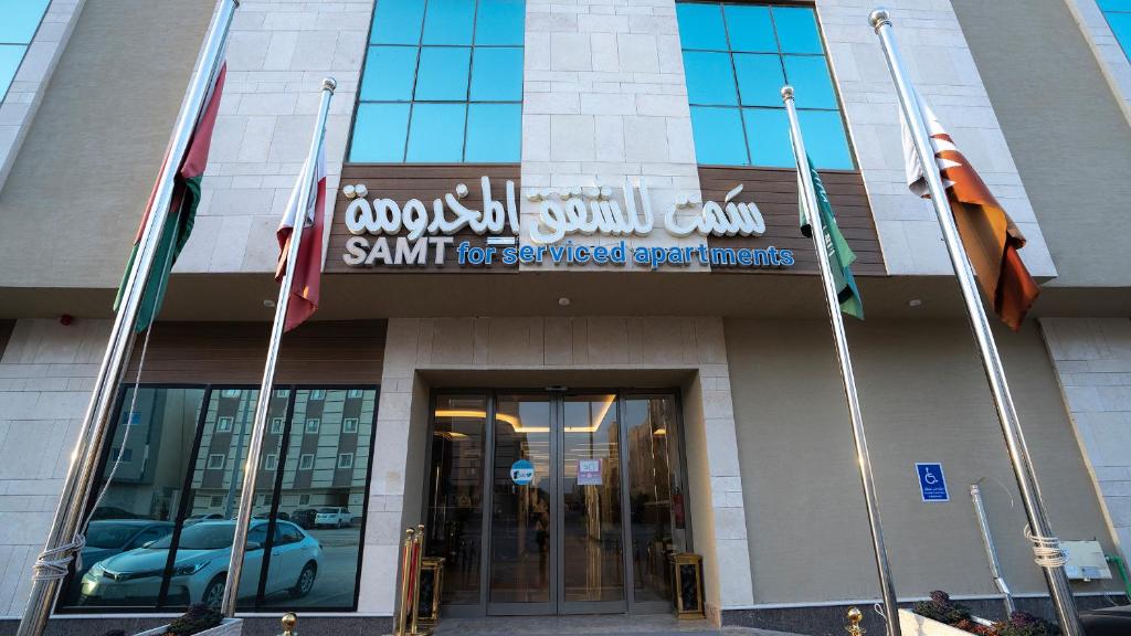 una señal en la parte delantera de un edificio con banderas en سمت للشقق المخدومة-النرجس en Riad