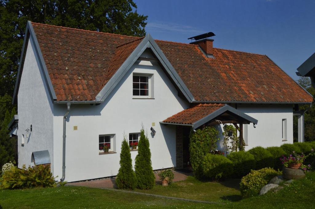 a white house with a red roof at Dom Pod Dębem in Majdy