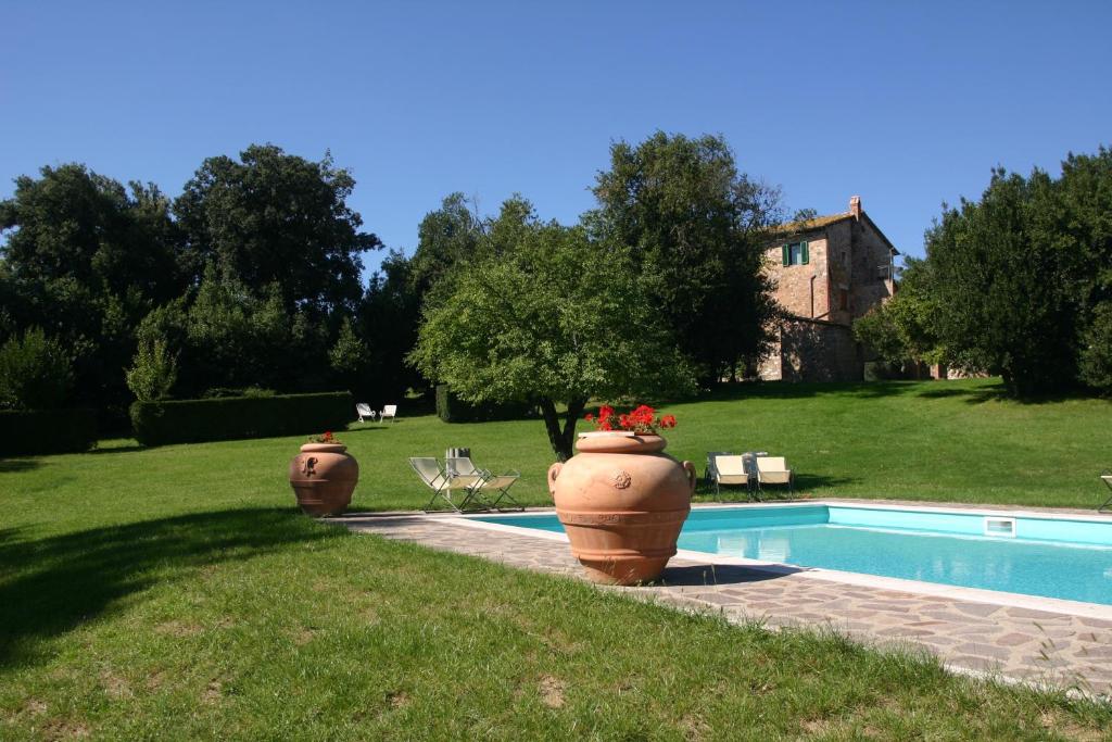 Dos jarrones grandes con flores junto a una piscina en Agriturismo Spazzavento, en Palazzone