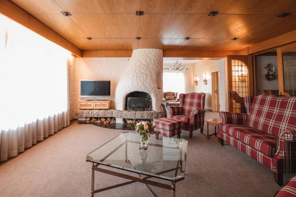 ein Wohnzimmer mit einem Kamin, einem Sofa und Stühlen in der Unterkunft Chalet Alpenstern in Oberstdorf