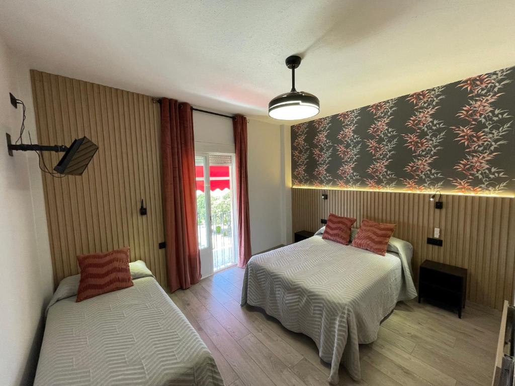 a room with two beds and a window at Hostal Calderón de la Barca in Zalamea de la Serena