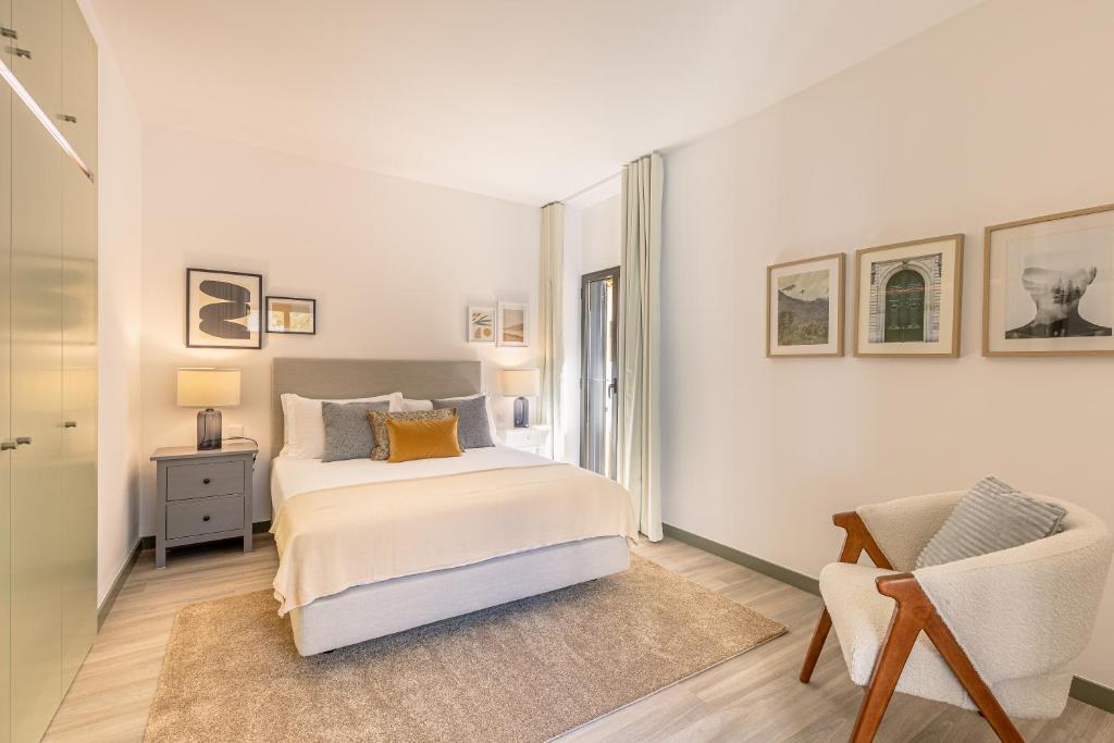 a white bedroom with a bed and a chair at Fort Bay Suite Apartments in Machico