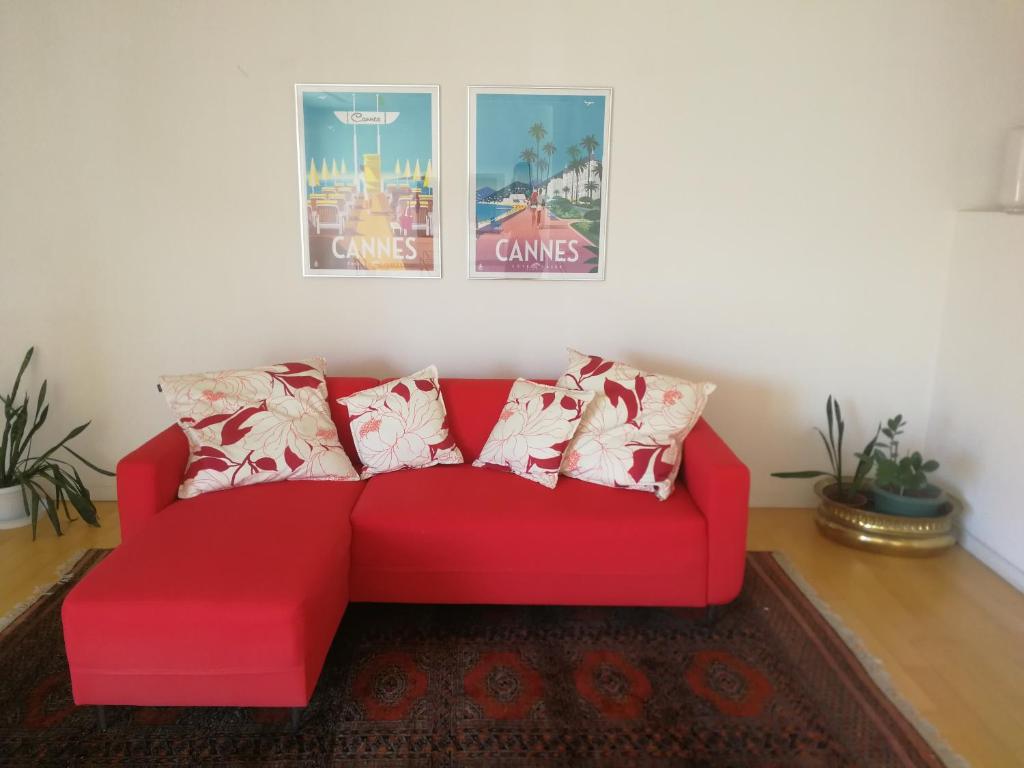 ein rotes Sofa im Wohnzimmer mit Bildern an der Wand in der Unterkunft Petit Paris - Incantevole appartamento in centro a Cannes a pochi passi dal Palais de Festival in Cannes