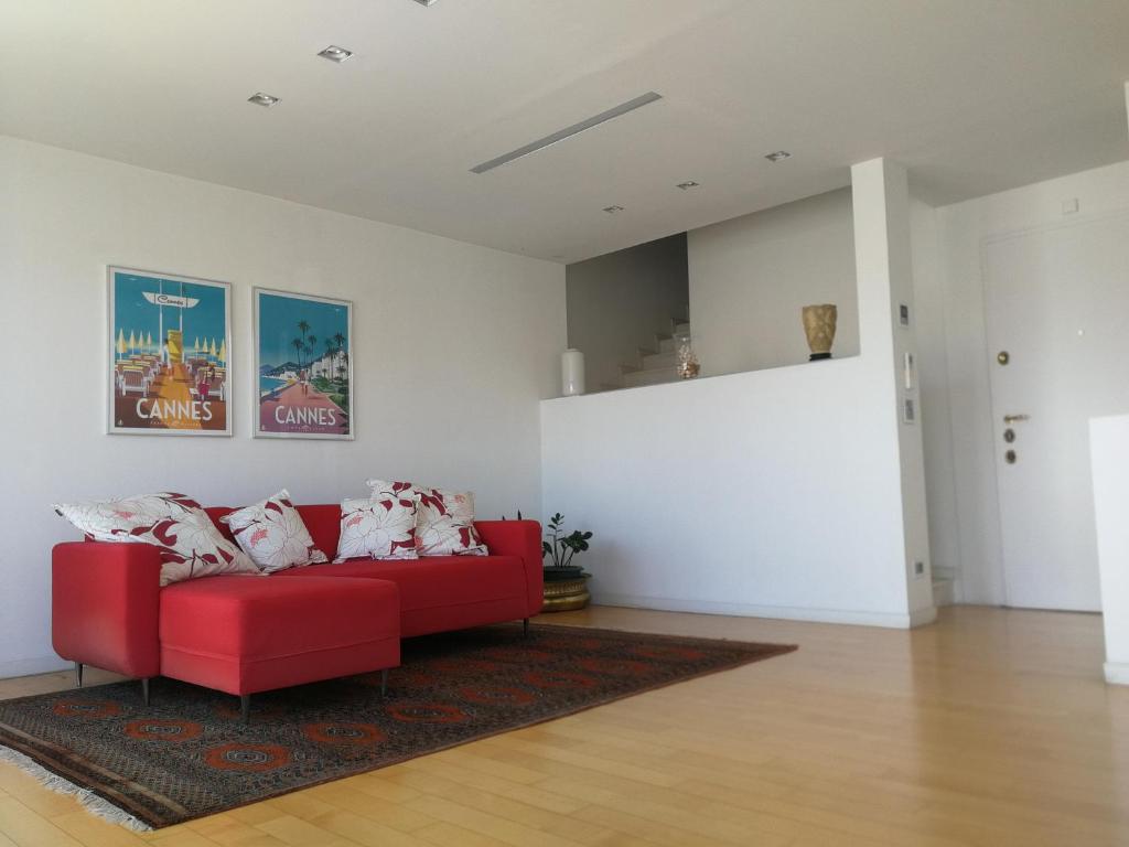 ein Wohnzimmer mit einem roten Sofa und einem Teppich in der Unterkunft Petit Paris - Incantevole appartamento in centro a Cannes a pochi passi dal Palais de Festival in Cannes