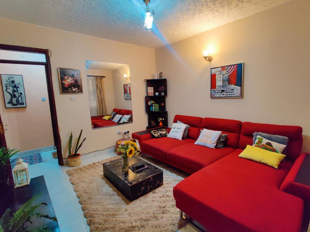 a living room with a red couch and a mirror at Modern & Comfy Mt. Kenya Sunset View Apartment in Kangaru