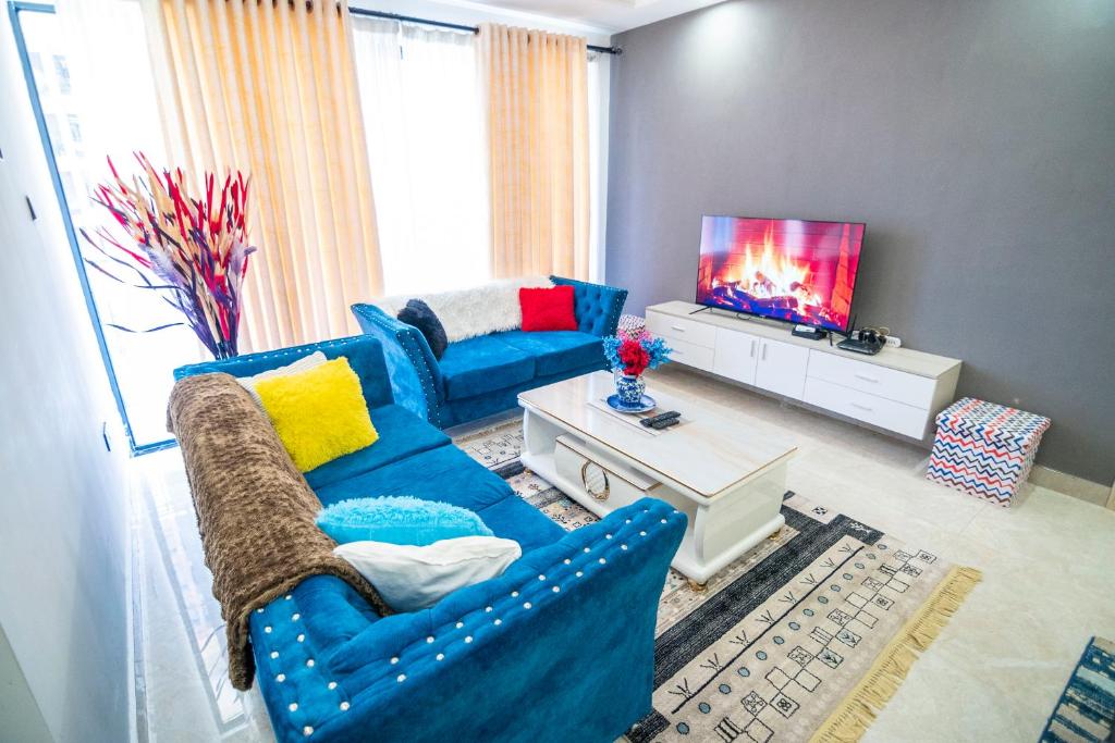 een woonkamer met een blauwe bank en een tv bij Kingara Road Apartment in Nairobi