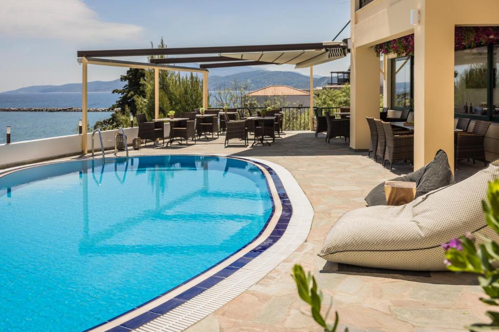 a swimming pool on a patio with chairs and tables at Valledi Village Hotel in Kymi