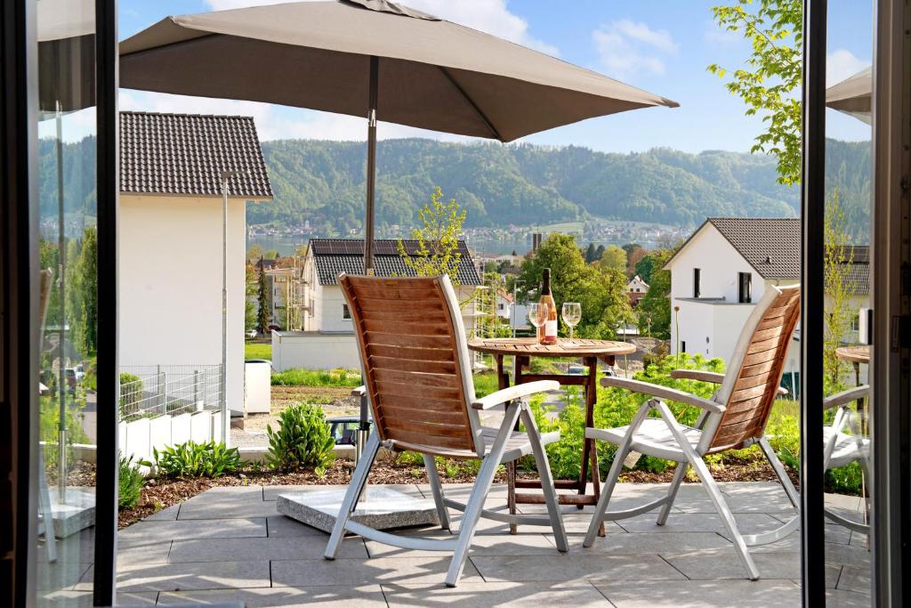 2 stoelen en een tafel met een parasol op een patio bij Ferienwohnung Maier in Bodman-Ludwigshafen