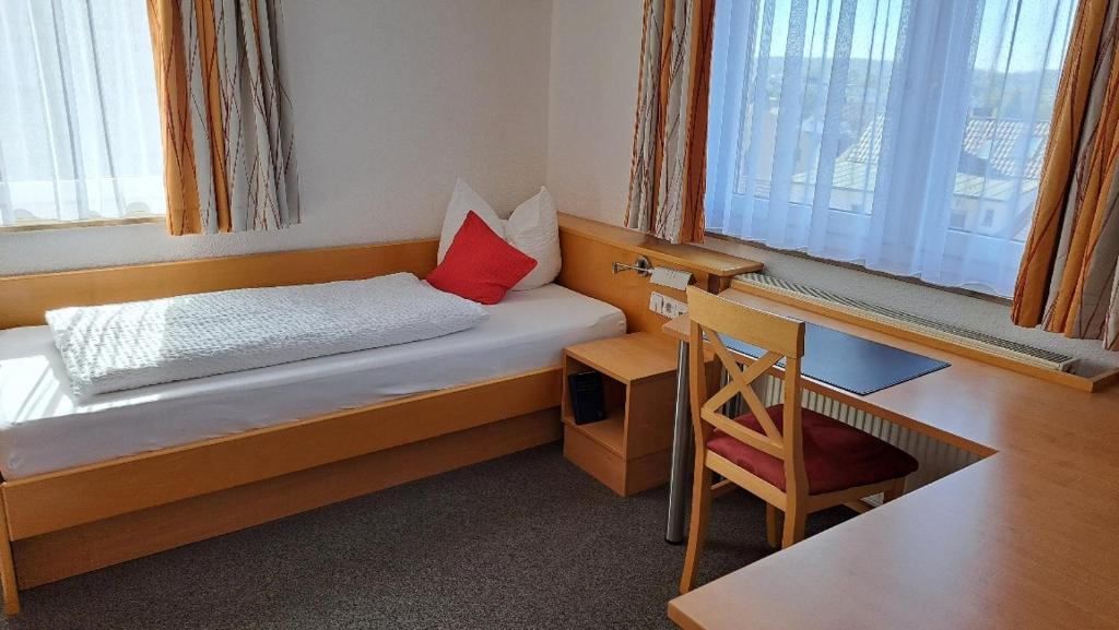 a bedroom with a bed with a desk and a red pillow at BB City Hotel in Böblingen