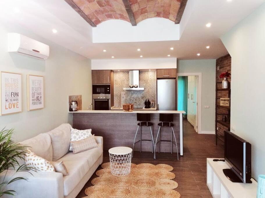 een woonkamer met een bank en een keuken bij Exclusivo Apartamento a 500 metros de la Playa in Castelldefels