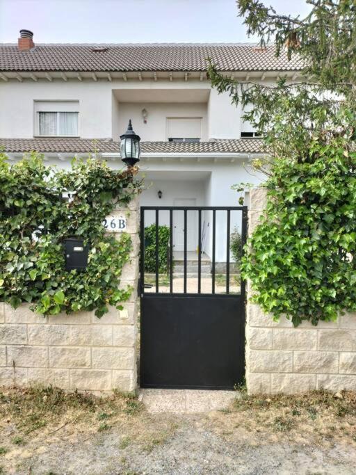 a black door on a white house with bushes at El Parangón in Herradón de Pinares