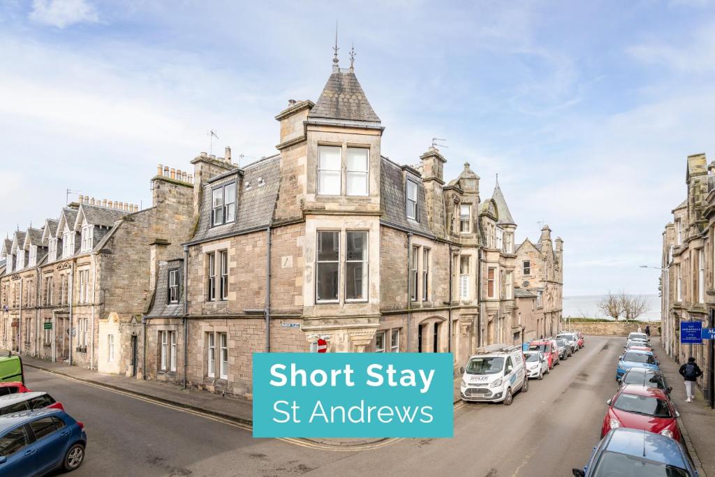 un antiguo edificio con coches aparcados en el lado de una calle en Murray Place - 5 min walk from The Old Course, en St Andrews