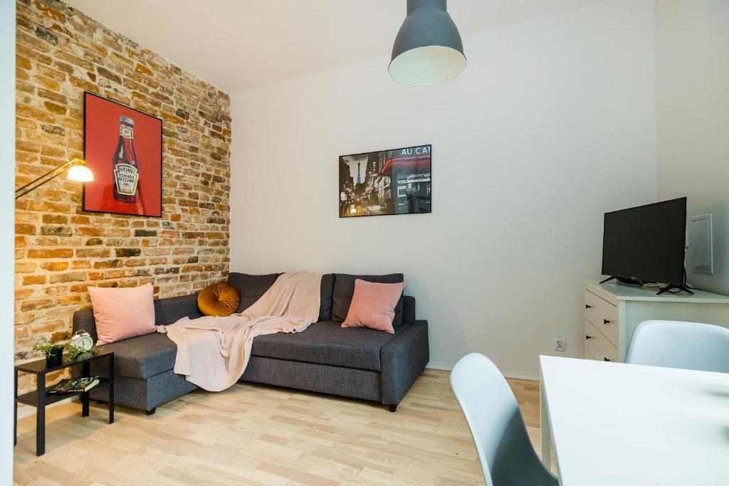 a living room with a couch and a brick wall at ShortStayPoland Joteyki (B125) in Warsaw