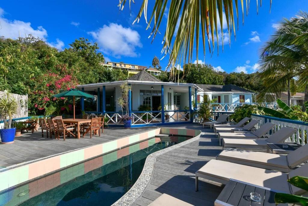 a pool with lounge chairs and a house at Villa Ordnance in English Harbour Town
