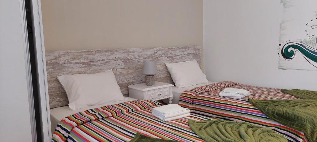1 dormitorio con 2 camas y manta a rayas en Surf House Helena, en Baleal
