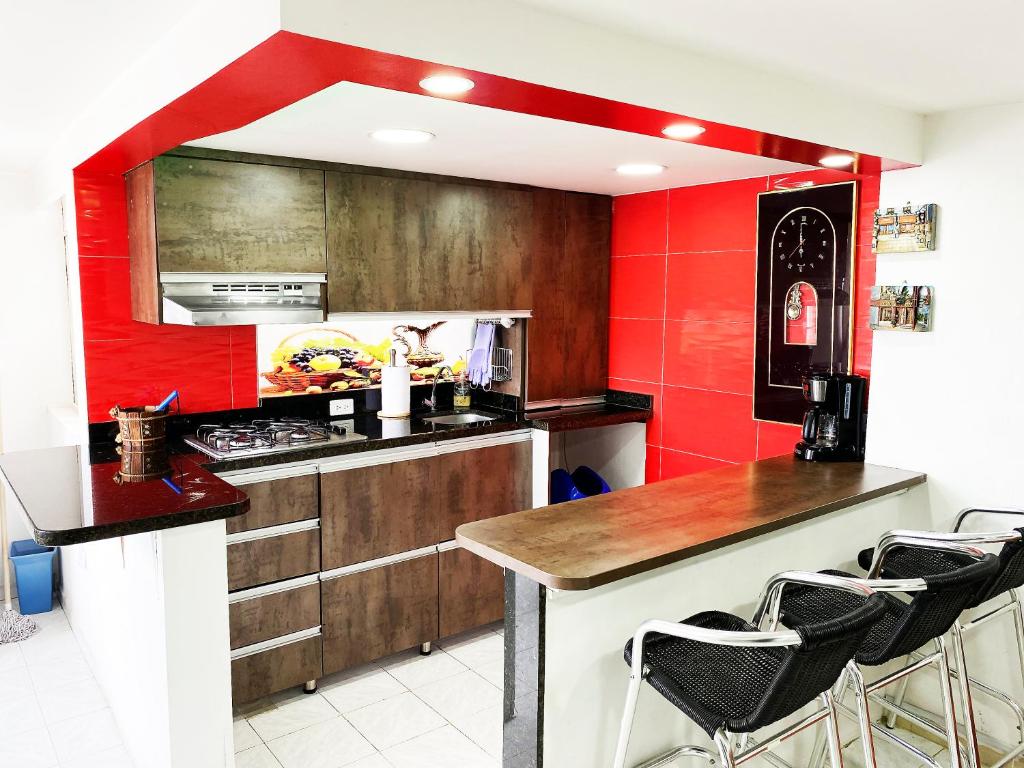 una cocina con paredes rojas y una barra con taburetes en The best location in Bogota, en Bogotá